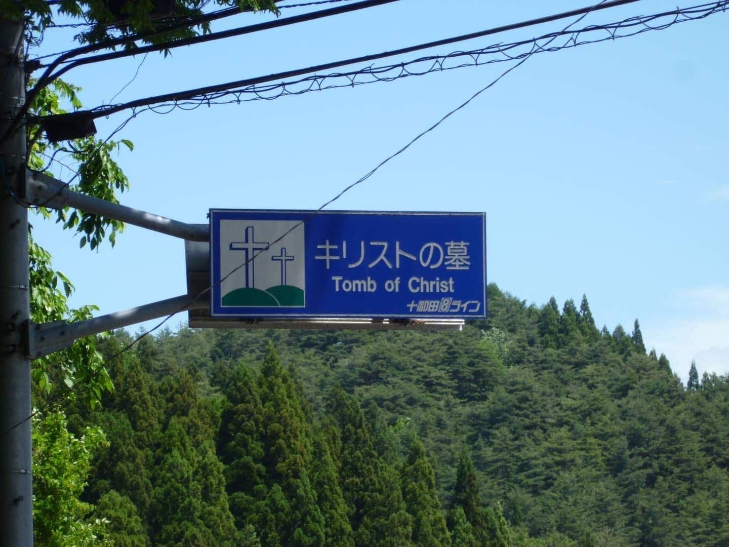 A bilingual road sign pointing toward the Tomb of Christ in Shingo